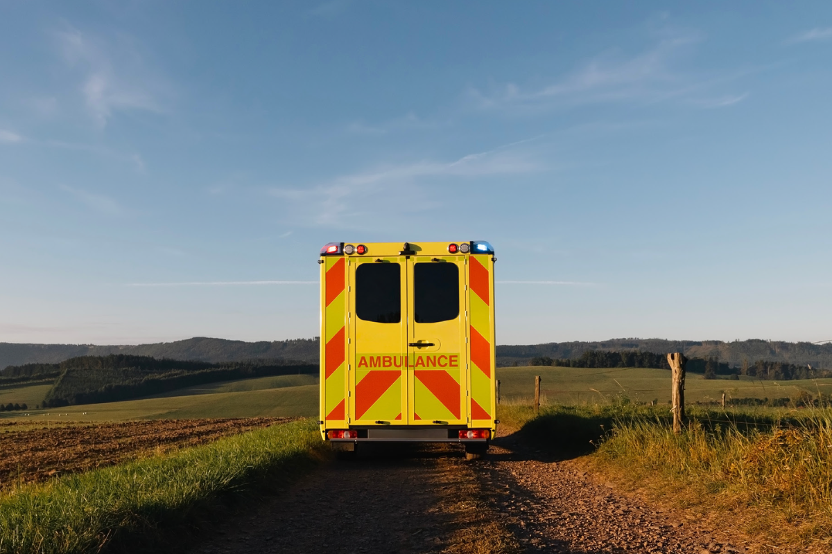 Back of a yellow ambulance on a dirt road in the country