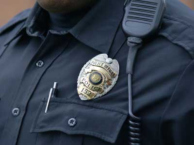 Close up of Police officer's blue uniform with pen, badge, and comms in view