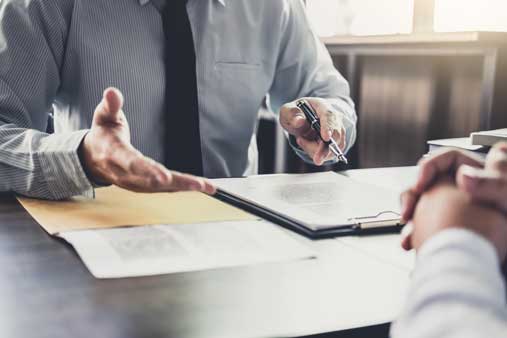 Man explaining document to another man across the table