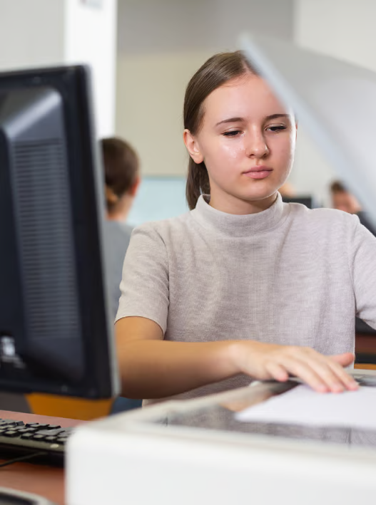 Female student working at her desk with a monitor and scanner