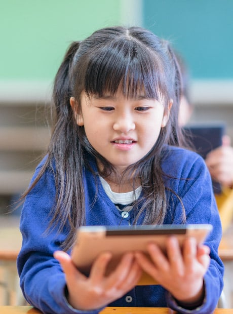 Young girl in classroom looking at a tablet
