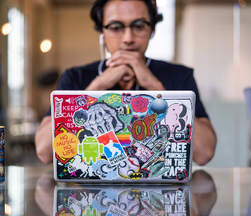 Person with headphones looking at a laptop.