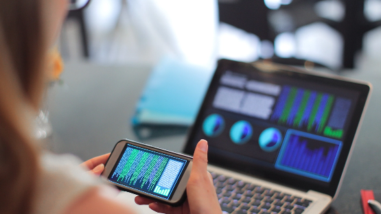 Person looking at phone and laptop.